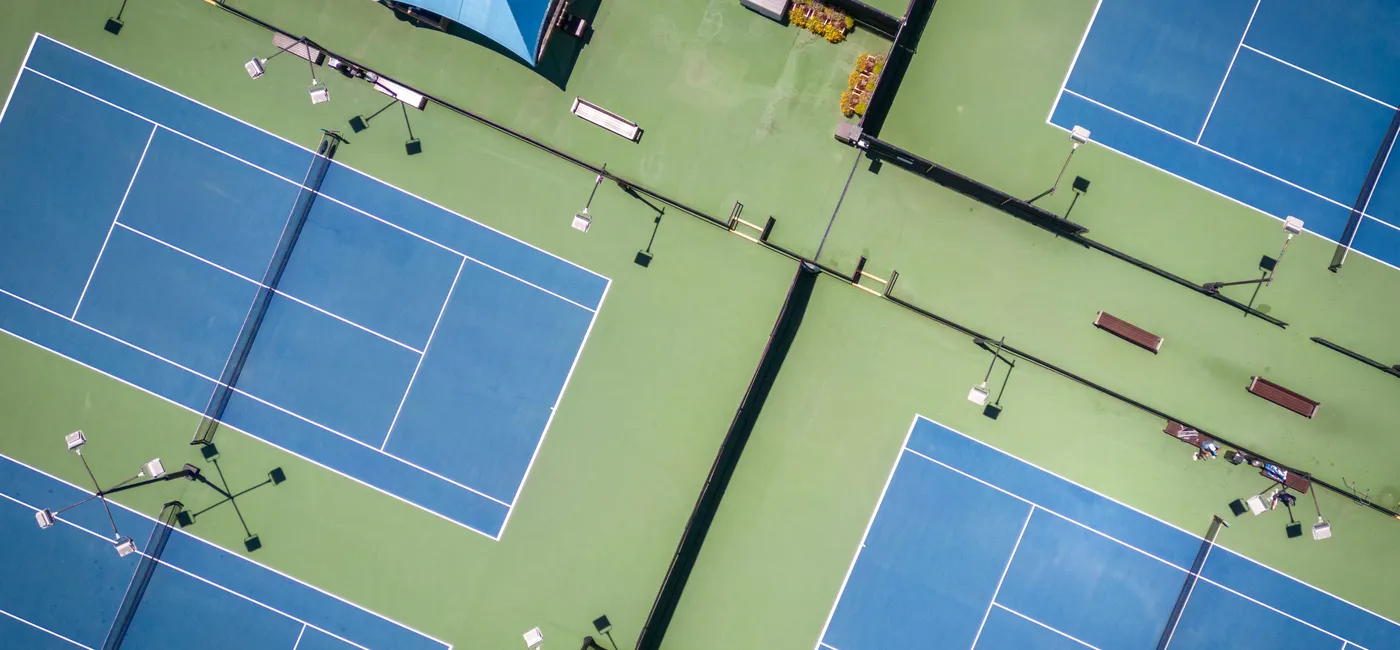 Aerial view of pristine, professionally maintained tennis courts at a premium tennis facility